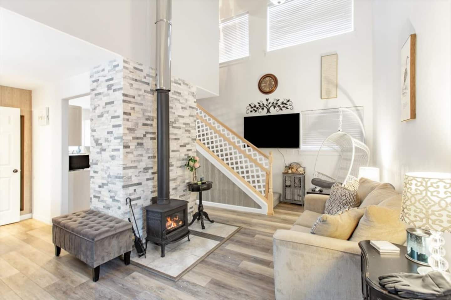 Bright cabin living room with a wood stove and high windows